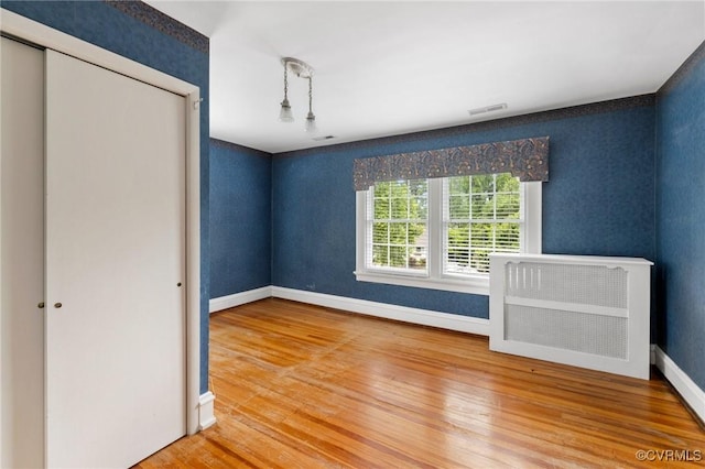 1601 Princeton Rd, Richmond, VA 23227 - unfurnished bedroom featuring wood finished floors, a closet, baseboards, radiator heating unit, and wallpapered walls