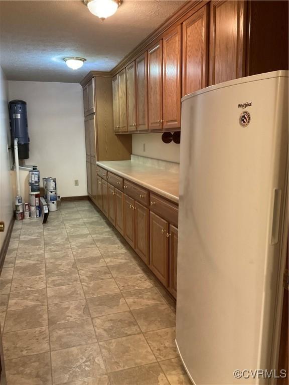 2458 Happy Hill Ln, Mechanicsville, VA 23111 - kitchen with freestanding refrigerator, light countertops, baseboards, a textured ceiling, and brown cabinets