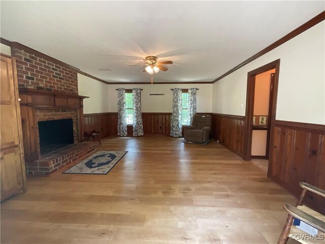 2458 Happy Hill Ln, Mechanicsville, VA 23111 - unfurnished living room featuring a wainscoted wall, a ceiling fan, light wood-style floors, crown molding, and a brick fireplace