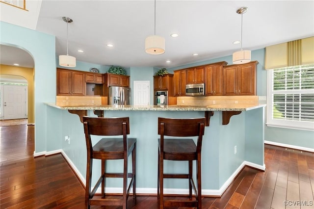4030 Water Overlook Blvd, Midlothian, VA 23112 - kitchen featuring appliances with stainless steel finishes, brown cabinets, arched walkways, light stone countertops, and dark wood-type flooring