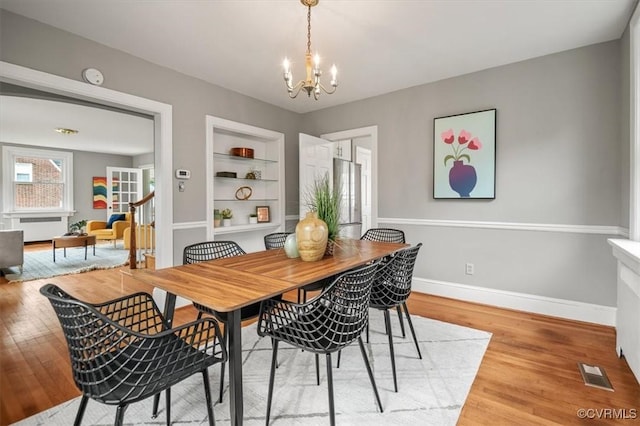 3204 Griffin Ave, Richmond, VA 23222 - dining room with a chandelier, radiator, built in shelves, light wood-style flooring, and baseboards