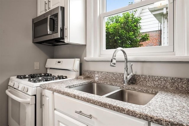 3204 Griffin Ave, Richmond, VA 23222 - kitchen featuring white gas range, stainless steel microwave, a sink, white cabinetry, and light stone countertops