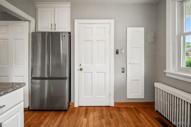 3204 Griffin Ave, Richmond, VA 23222 - kitchen featuring freestanding refrigerator, radiator, light wood finished floors, white cabinets, and dark stone counters