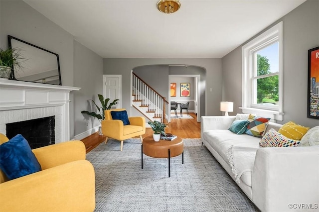 3204 Griffin Ave, Richmond, VA 23222 - living room featuring arched walkways, wood finished floors, stairs, a fireplace, and baseboards