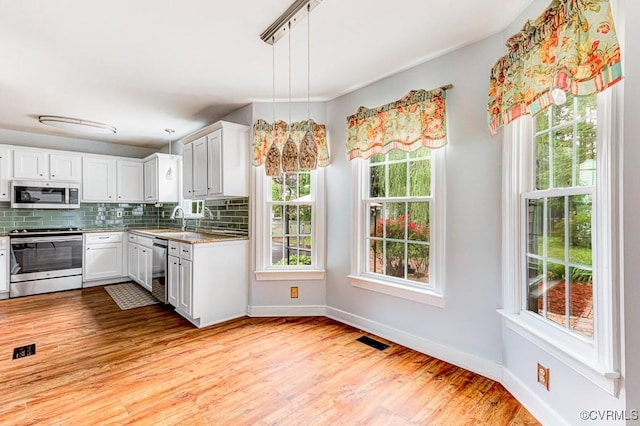 9214 Hunters Chase Dr, Mechanicsville, VA 23116 - kitchen with appliances with stainless steel finishes, decorative backsplash, light wood finished floors, white cabinetry, and decorative light fixtures