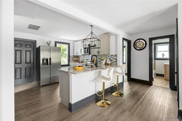327 S 12th Ave, Hopewell, VA 23860 - kitchen with stainless steel appliances, a peninsula, light stone counters, a kitchen bar, and tasteful backsplash