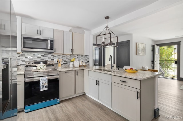 327 S 12th Ave, Hopewell, VA 23860 - kitchen with stainless steel appliances, a peninsula, a sink, light wood finished floors, and decorative backsplash