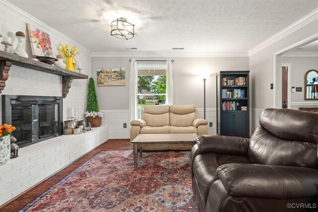 1146 Wicker Dr, Colonial Heights, VA 23834 - living area featuring a textured ceiling, ornamental molding, wainscoting, wood finished floors, and a brick fireplace