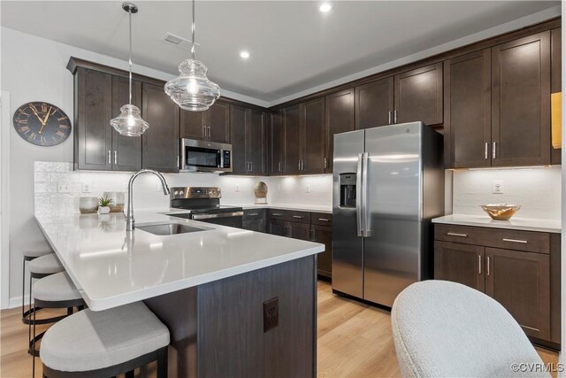 9210 Magellan Pkwy Unit A, Richmond, VA 23060 - kitchen with appliances with stainless steel finishes, a sink, a kitchen bar, light wood finished floors, and dark brown cabinets