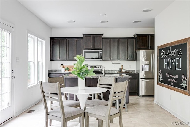 8412 Morocco Pl, Moseley, VA 23832 - kitchen with stainless steel appliances, plenty of natural light, a center island with sink, and dark brown cabinetry