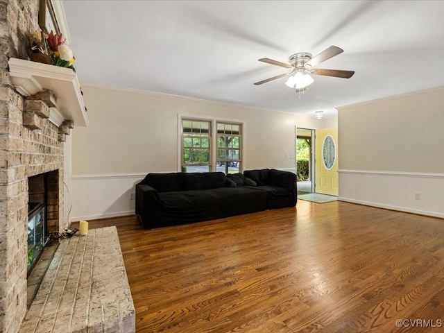 13610 Old Stage Rd, North Prince George, VA 23860 - living room with a brick fireplace, wood finished floors, a ceiling fan, a wainscoted wall, and ornamental molding