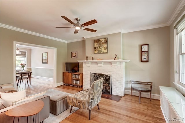 3429 Hanover Ave, Richmond, VA 23221 - living area featuring light wood-style flooring, crown molding, a ceiling fan, a brick fireplace, and baseboards