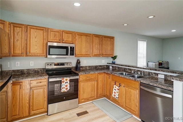3107 Q St, Richmond, VA 23223 - kitchen with stainless steel appliances, recessed lighting, brown cabinets, light wood-style floors, and dark stone counters