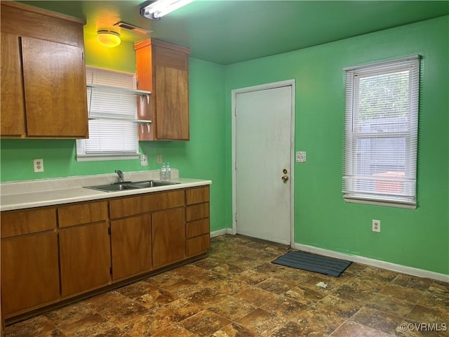 609 Carter St, Petersburg, VA 23803 - kitchen featuring a sink, light countertops, baseboards, brown cabinets, and dark stone finish flooring