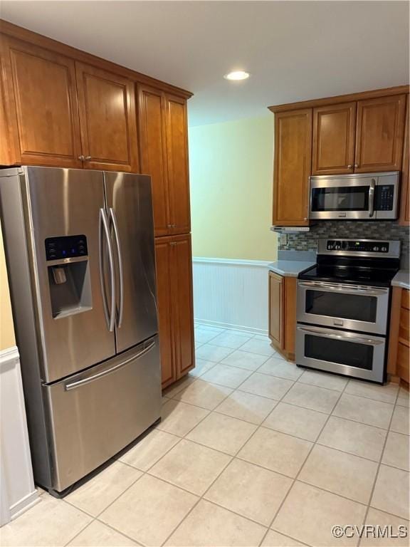 12605 Long Branch Ct, Chesterfield, VA 23832 - kitchen with stainless steel appliances, brown cabinetry, wainscoting, light tile patterned floors, and decorative backsplash