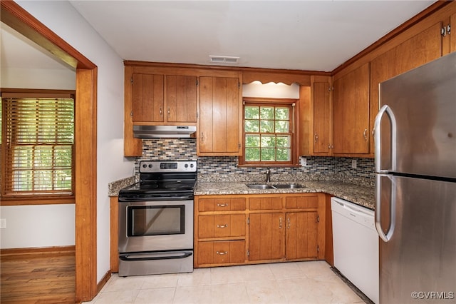 10216 Greglynn Rd, North Chesterfield, VA 23236 - kitchen with stainless steel appliances, under cabinet range hood, a sink, brown cabinetry, and tasteful backsplash