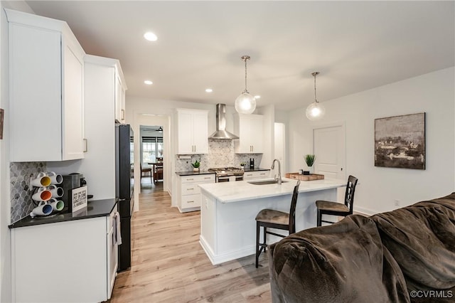 720 Chapman St, Ashland, VA 23005 - kitchen featuring wall chimney range hood, a sink, stainless steel gas range, freestanding refrigerator, and a breakfast bar