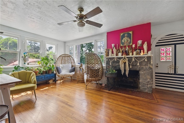 290 Circle Dr, Port Haywood, VA 23138 - living room featuring wood-type flooring, a textured ceiling, ceiling fan, and a stone fireplace