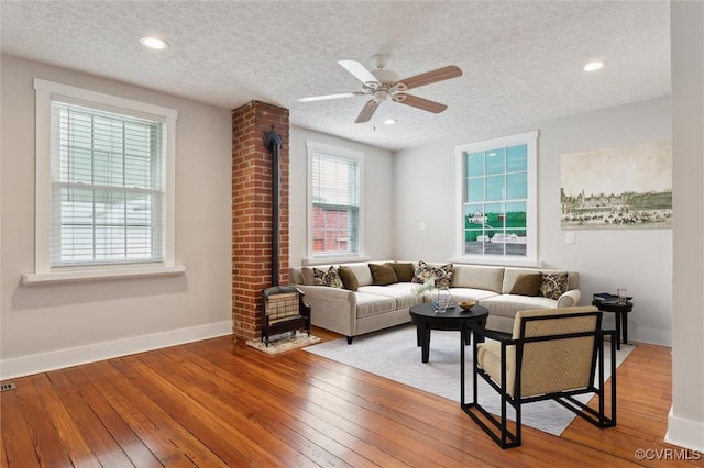 29898 The Trl, Shacklefords, VA 23110 - living area featuring a wood stove, a textured ceiling, baseboards, hardwood / wood-style floors, and a ceiling fan