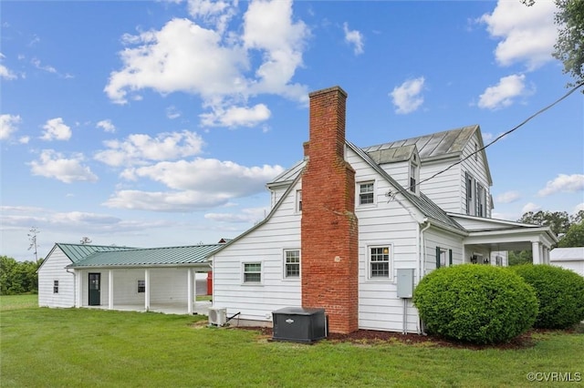 29898 The Trl, Shacklefords, VA 23110 - view of side of home featuring a chimney, a yard, central AC unit, metal roof, and a standing seam roof