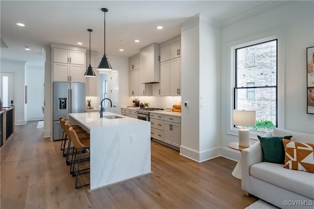 425 W 7th St, Richmond, VA 23224 - kitchen featuring a sink, high end appliances, wall chimney exhaust hood, wood finished floors, and a kitchen breakfast bar