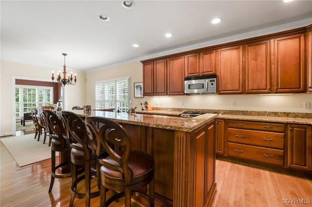 561 Hill Grove Rd, Manakin Sabot, VA 23103 - kitchen with stainless steel appliances, light stone countertops, a breakfast bar area, light wood-type flooring, and an island with sink