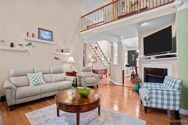 9085 Winter Spring Dr, Mechanicsville, VA 23116 - living room featuring wood finished floors, stairs, decorative columns, a glass covered fireplace, and a towering ceiling