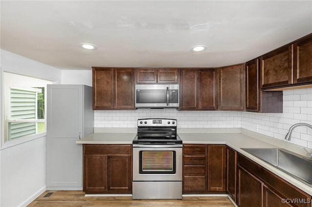3027 Supply Rd, Port Royal, VA 22436 - kitchen featuring appliances with stainless steel finishes, a sink, light wood-style flooring, decorative backsplash, and dark brown cabinetry
