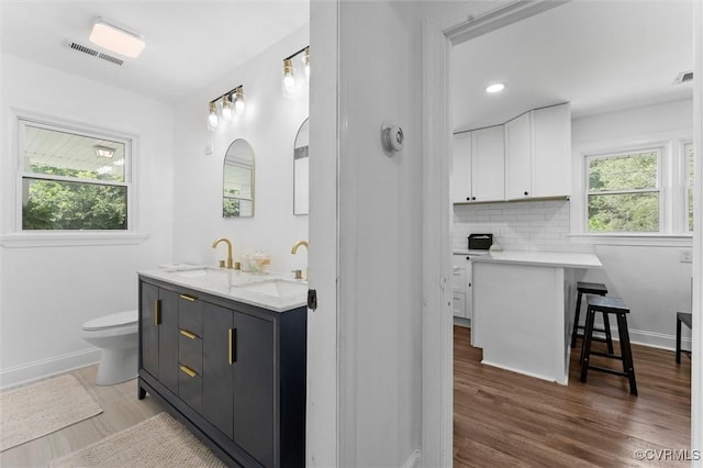1311 Dinwiddie Ave, Hopewell, VA 23860 - full bath featuring double vanity, toilet, wood finished floors, tasteful backsplash, and baseboards