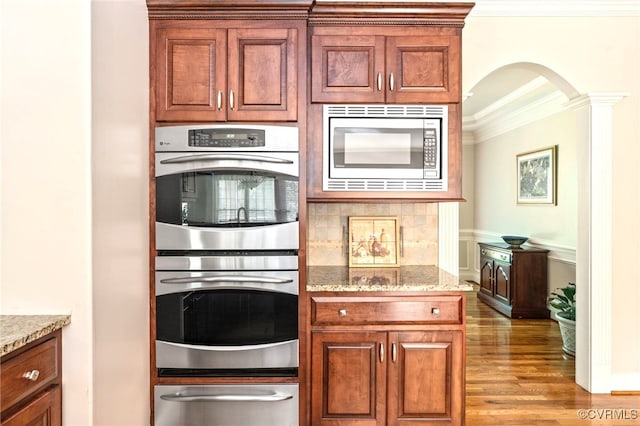 2220 French Hill Ter, Powhatan, VA 23139 - kitchen featuring appliances with stainless steel finishes, a warming drawer, crown molding, arched walkways, and light wood finished floors