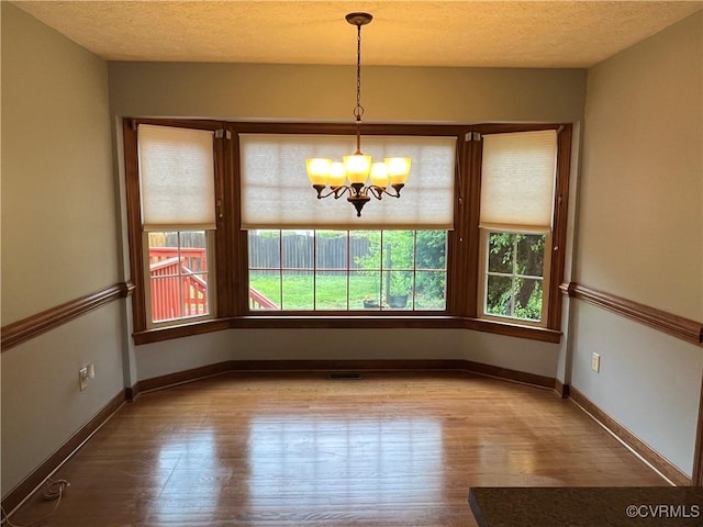 8172 Dunfee Ln, Mechanicsville, VA 23111 - unfurnished dining area featuring wood finished floors, a chandelier, and baseboards