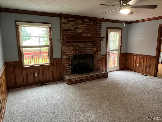 8172 Dunfee Ln, Mechanicsville, VA 23111 - unfurnished living room with wainscoting, a textured ceiling, a ceiling fan, plenty of natural light, and a brick fireplace