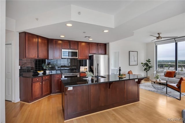 1101 Haxall Pt Unit U1001, Richmond, VA 23219 - kitchen with stainless steel appliances, decorative backsplash, light wood-style flooring, dark stone countertops, and a kitchen bar