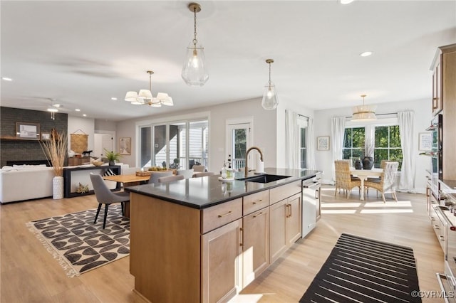 9463 Angels Share Dr, New Kent, VA 23124 - kitchen featuring a sink, dark countertops, light wood-type flooring, appliances with stainless steel finishes, and an island with sink