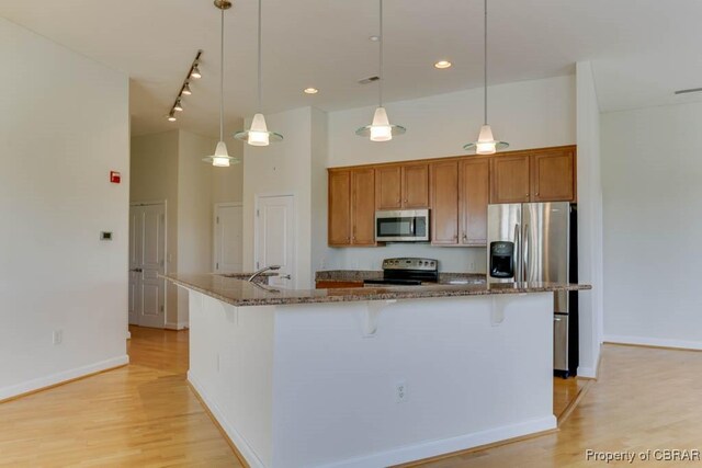 670 Town Center Dr Unit 418, Newport News, VA 23606 - kitchen with appliances with stainless steel finishes, brown cabinetry, a kitchen bar, dark stone countertops, and a high ceiling