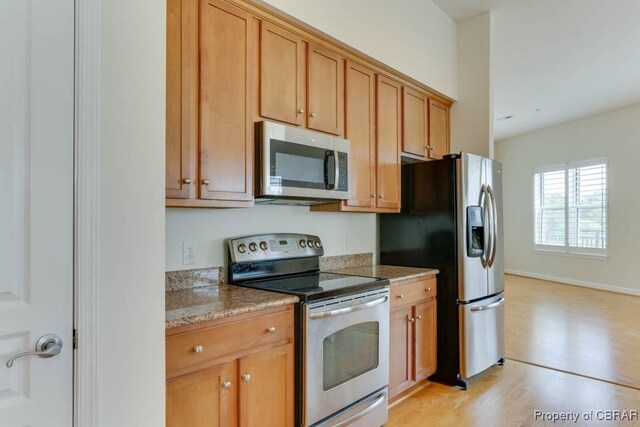 670 Town Center Dr Unit 418, Newport News, VA 23606 - kitchen with stainless steel appliances, light wood finished floors, light stone counters, and brown cabinetry