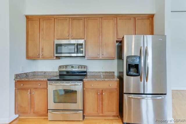 670 Town Center Dr Unit 418, Newport News, VA 23606 - kitchen with appliances with stainless steel finishes, brown cabinets, light wood-style floors, and light stone counters