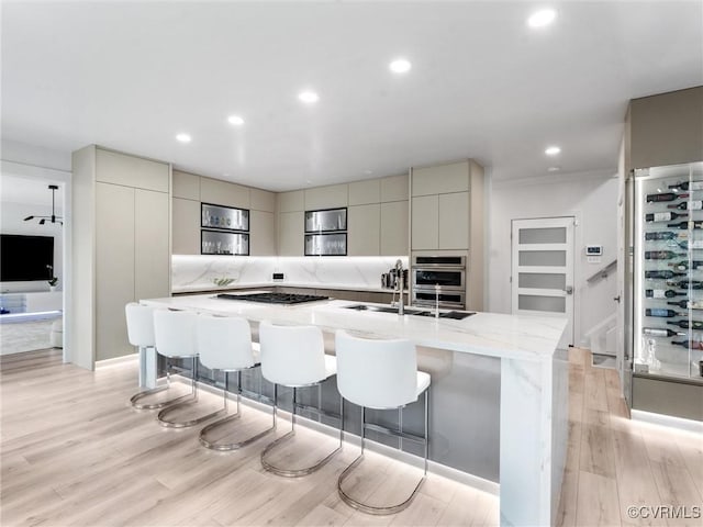 11507 Barrington Bridge Ter, Henrico, VA 23233 - kitchen with modern cabinets, appliances with stainless steel finishes, an island with sink, light wood-style flooring, and a kitchen bar