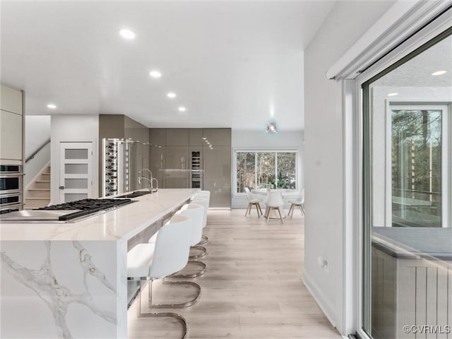 11507 Barrington Bridge Ter, Henrico, VA 23233 - kitchen featuring stainless steel stovetop, light stone counters, light wood-style flooring, recessed lighting, and a large island with sink