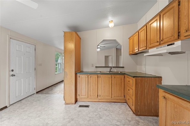 1426 Rolling Acres Rd, Emporia, VA 23847 - kitchen with under cabinet range hood, a sink, ceiling fan, dark countertops, and brown cabinetry