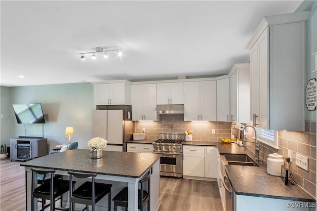 9300 Adkins Rd, Charles City, VA 23030 - kitchen featuring appliances with stainless steel finishes, under cabinet range hood, dark countertops, a sink, and decorative backsplash