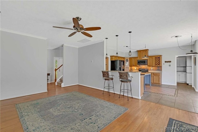 2024 Sarahs Cove Dr, Gloucester, VA 23072 - kitchen with black fridge, stainless steel microwave, a ceiling fan, tasteful backsplash, and a kitchen breakfast bar