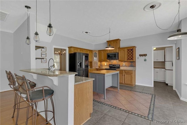 2024 Sarahs Cove Dr, Gloucester, VA 23072 - kitchen featuring black appliances, tasteful backsplash, tile patterned floors, a peninsula, and a center island