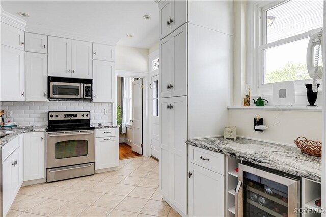 3029 Monument Ave Unit U6, Richmond, VA 23221 - kitchen featuring stainless steel appliances, wine cooler, backsplash, light tile patterned floors, and white cabinets