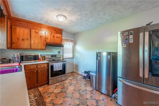 18517 Depot Rd, Mc Kenney, VA 23872 - kitchen featuring appliances with stainless steel finishes, under cabinet range hood, brown cabinets, light countertops, and a textured ceiling