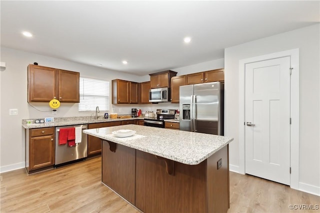 7128 Iron Gall Ln, Ruther Glen, VA 22546 - kitchen with stainless steel appliances, light wood-type flooring, a breakfast bar area, a center island, and light stone counters