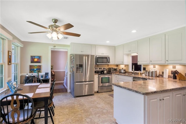 1468 Peppercorn Ln, Suffolk, VA 23432 - kitchen featuring appliances with stainless steel finishes, a peninsula, a sink, ceiling fan, and dark stone countertops