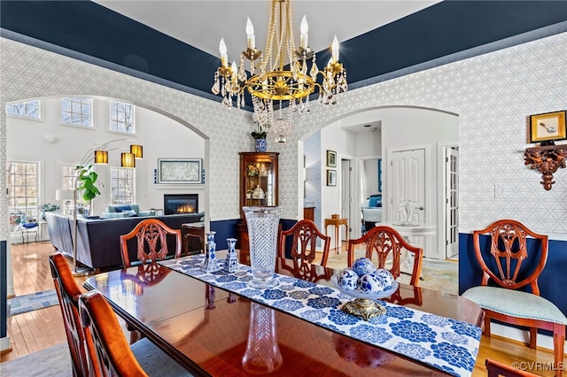 5225 Clipper Cove Rd, Chesterfield, VA 23112 - dining room with arched walkways, wood finished floors, a glass covered fireplace, a chandelier, and wallpapered walls