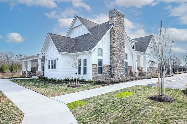 7547 Sedge Dr, New Kent, VA 23124 - view of side of home with board and batten siding, stone siding, a shingled roof, a lawn, and a chimney