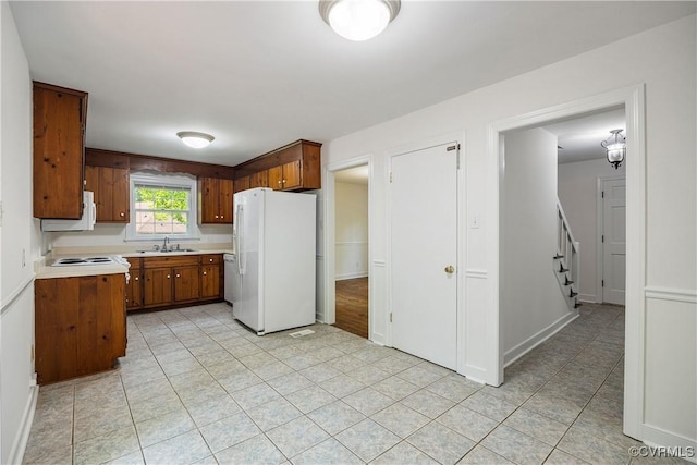 13917 Barnes Spring Rd, Midlothian, VA 23112 - kitchen featuring white appliances, brown cabinetry, light countertops, light tile patterned floors, and a sink